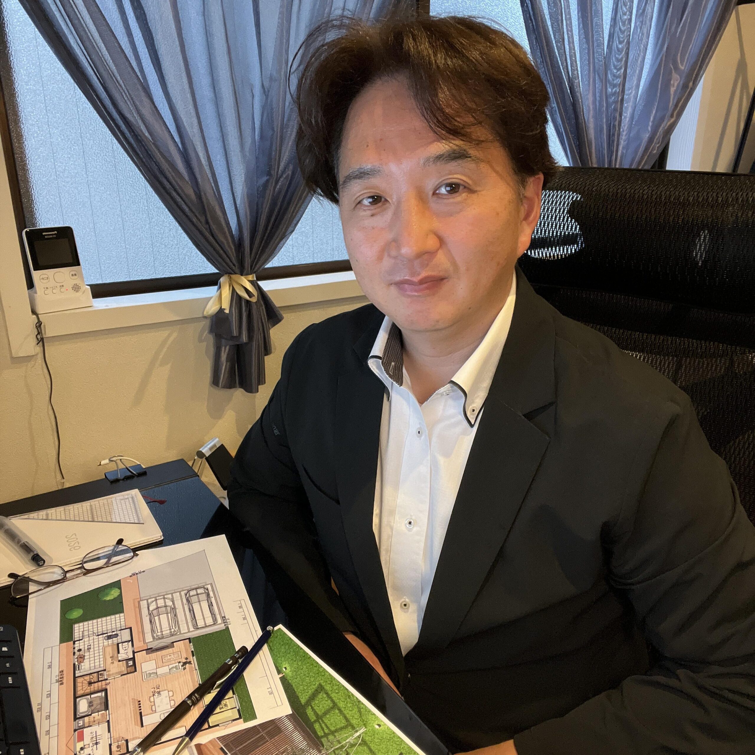 注文住宅の間取り図を確認する宅地建物取引士・二級建築士の岩崎卓也